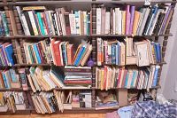 Full view of three-shelf bookcase loaded with assorted hardcover and paperback books