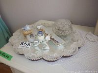 Full view of glass mirrored tray containing trinket boxes, porcelain dish with brooches, and decorative figurines