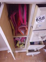 Open cabinet drawer showing several pink makeup bags of different sizes and patterns stacked inside compartments