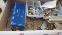 Plastic trays containing mixed jewelry and blue Parker box
