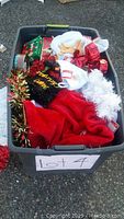 Photo of a bin filled with new Christmas decoration items including ribbons, stockings, and tinsel items from an overhead angle.