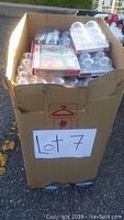 Large tall cardboard box filled with sealed packages of clear Christmas ball ornaments and other holiday items, visible from top