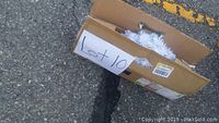 Box placed outdoors with 'Lot 10' label, showing folded tree inside partially visible.