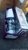 Large purple bin filled with various sealed Christmas decoration items including holiday decorative picks and ornament hooks.