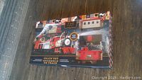 Front view of packaged F.A.O. Schwarz Classic Motorized Train Set showing the 4 train cars inside the box and product branding.