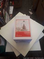 Photo of the boxed Christmas cloche showing the product image on the packaging, depicting a miniature Christmas village inside a glass dome with pre-lit lights.