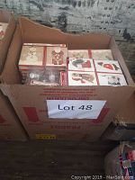 Cardboard box packed with multiple boxed sets of Christmas cards and a pack of silver Christmas ornaments