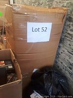 Large cardboard box labeled Lot 52, containing the Christmas tree, box shows damage and tape repairs.