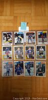 Photo shows 12 hockey cards laid out on wooden floor. Cards include 11 Opee Chee 1980s hockey cards predominantly featuring Winnipeg Jets players and one 1985 Topps Wayne Gretzky Record Breaker card.