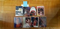 Photo showing eight basketball trading cards arranged on floor, featuring Kobe Bryant, LeBron James, and Michael Jordan cards among others.