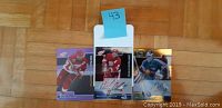 Photo showing three autographed 2002 ITG hockey cards featuring Steve Yzerman, Nicklas Lidstrom, and Miikka Kiprusoff on a wooden floor with an identifier '43' taped above.