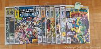 Photo showing a collection of 10 Spider-Man comic books laid out in a row, covers visible.