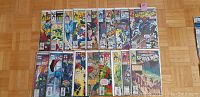 Photo showing 19 Amazing Spider-Man comic books arranged in two rows on a wooden floor, covers visible