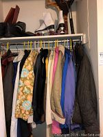 Closet section showing multiple outdoor jackets and snow bibs on hangers.