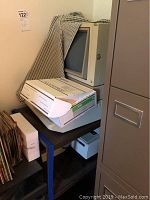 Overview of Apple IIe and Okidata printer under cloth on shelving