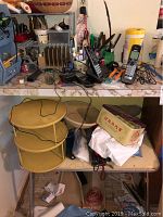 Overview of lot items including cordless phones, small folding table, beige plastic lazy Susan, plastic rack with nail polishes, various office supplies and accessories.