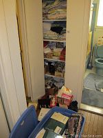 Photo showing a storage closet with multiple folded linens and towels on shelves, boxes and bins on floor.