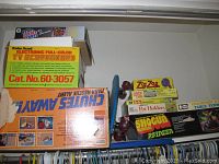 Boxes of vintage games and toys stacked in closet space including Chutes Away game box, Radio Shack Electronic Full-Color TV Scoreboard box, and others.