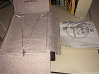 Cross necklace displayed in Jewelry Artisans suede roll alongside the original receipt