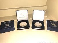 Two American Eagle silver bullion coins in black presentation boxes along with blue display boxes labeled 'American Eagle Silver Bullion Coin UNITED STATES MINT'