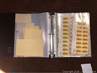 Open binder showing mint stamps in protective sleeves arranged in strips and sheets.