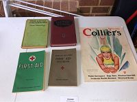 Photo showing five vintage printed items: a 1936 Collier's magazine with a female swimmer on the cover, two American Red Cross first aid books (one green booklet and one beige textbook), a 1926 Baptist Hymnal with dark red hardcover, and a 1916 Thomas Nelson Page green hardcover book titled 'Two Little Confederates'. The items lay on a white surface with a brick wall background.