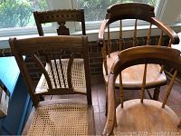 Four vintage wooden chairs: two with cane seats and carved backs, two with spindle backs and wooden seats, one with back damage