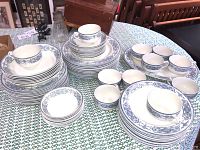 Full set displayed on table from left angle, showing stacks of plates, bowls, cups and saucers.