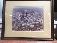 Framed aerial photograph showing downtown Atlanta with buildings, streets, and highway ramps visible, mounted with a beige mat and a dark wood frame.