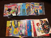 Photo shows a collection of approximately 23 vintage children's records arranged in two rows on a dark surface. The record sleeves feature beloved characters from Sesame Street, The Muppets, and Mr. Rogers. Covers include colorful illustrations of Kermit the Frog, Big Bird, and other puppets.