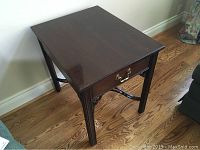 Side view of Ethan Allen hardwood side table with single drawer and polished wood surface