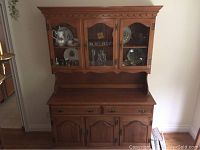 Maple buffet and hutch with upper glass doors and lower cabinet doors, showing overall front profile.
