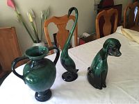 Photo showing the three pottery items: double handled vase, dog figurine, long neck bird figurine on a table.