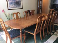 Full view of extended maple dining table with 8 matching chairs around it in a dining room setting.