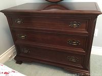 Front view of cherry wood dresser showing three full-width drawers and brass bail handles