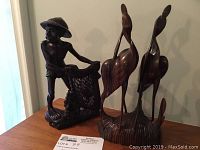 Overall photo showing the fisherman carving with net next to two bird carvings on shared base.