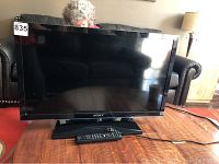 Front view of Sony 32" TV on stand with remote on wooden table.