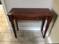 Front view of rectangular oak hall table showing tabletop, drawer, and legs.