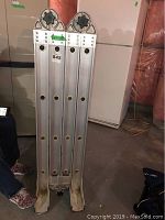Front view of folded Featherlite aluminum folding ladder showing locking mechanisms and feet.