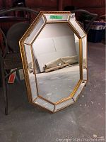 Front view of octagonal beveled mirror showing gold trim and light wear