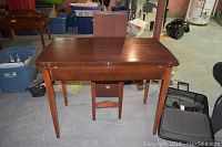 Vintage light mahogany folding table shown open and closed with extra leaf behind.