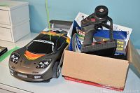 Side view of Traxxas Nitro 4-Tec Model 4810 remote control car beside box containing remote and manual.