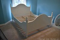 Full view of assembled white wooden bed frame showing headboard, footboard, and side rails in a room