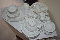 Full set overview showing plates stacked, teapot, saucers, tea cups, creamer, and sugar bowl on table.