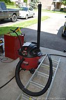 Photo showing the complete Craftsman wet/dry vacuum with hose, extension wand, and nearby ladder and background cars.