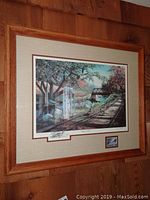 Framed signed commemorative print featuring ducks by Ken Zylla mounted on wood wall
