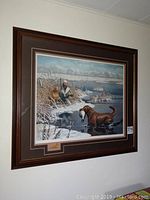 Front view of framed print showing the hunting scene with two dogs and hunter, with wooden duck emblem in matting.