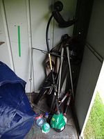 Gas Weed Eater trimmer with extra line, clippers, and Toro electric leaf blower grouped close in shed corner.