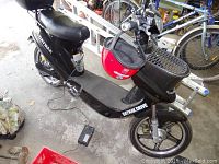 Right-side view of black scooter with charger plugged into charging port