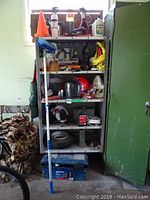 Full shelving unit displaying various tools, Skidoo helmet, oil bottles, tire, tool box and other items